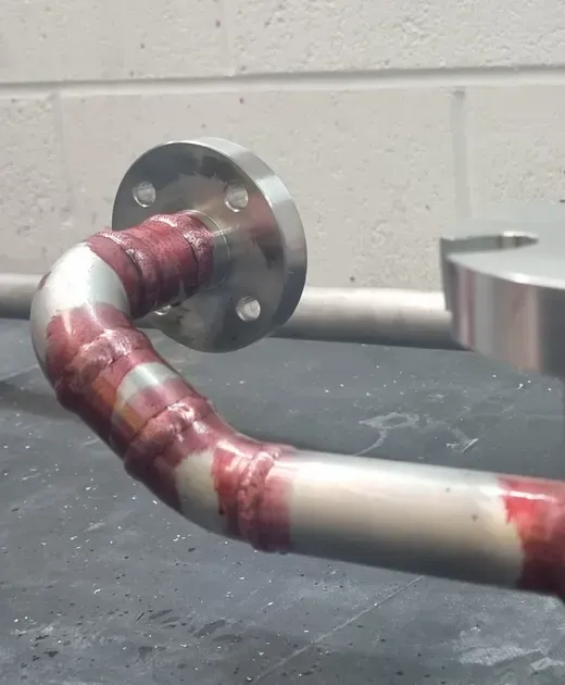 Red dye penetrant indications on a stainless steel pipework spool