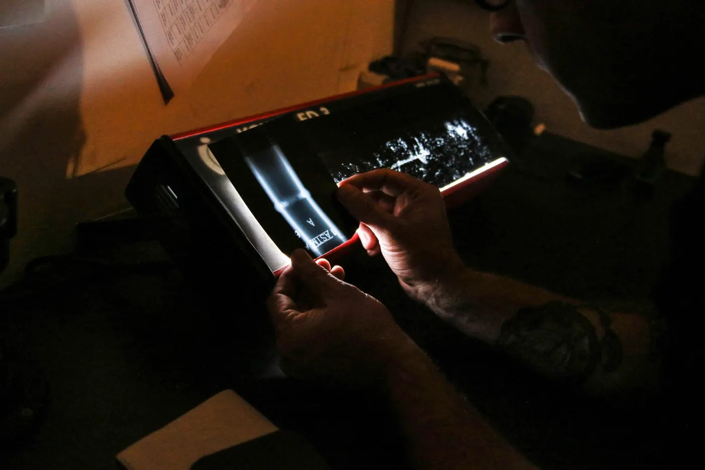 Technician holding a weld radiograph up to a film viewer