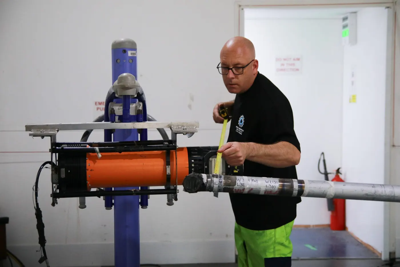 Technician setting up an X-ray tube on a pipe sample in the radiography bay